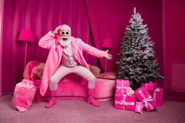 Photo of senior bearded male santa claus point tree gifts cool boots fur coat fluffy nighty hat sunglasses pink new year celebration decor