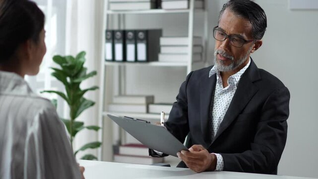 Human resources manager is sitting at his desk and interviewing a young applicant