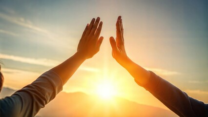 Two hands reaching out in joy at sunset against a bright background for "high five" concept