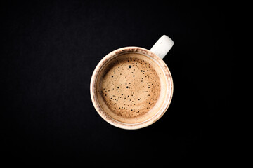 Cup of coffee on dark paper background. Close up. Copy space.
