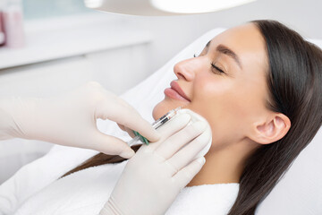 Cosmetologist doing injections for lips augmentation and anti wrinkle in nasolabial folds of young...