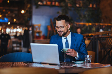 Obraz premium Businessman Enjoying Coffee While Working on Laptop in Cafe