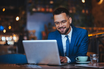 Businessman Smiling While Working on Laptop in Cozy Cafe