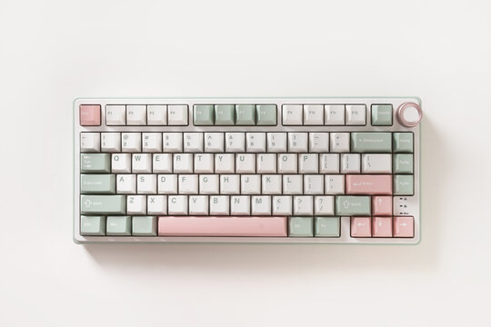 Modern mechanical keyboard on white background. Minimal style and design keyboard. Custom build keyboard. Colorful key pastel creamy pink and green cap. Top view.