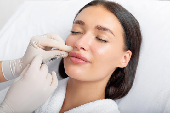 Beauty specialist making injection in female patient lips, lip augmentation and correction procedure in cosmetology salon
