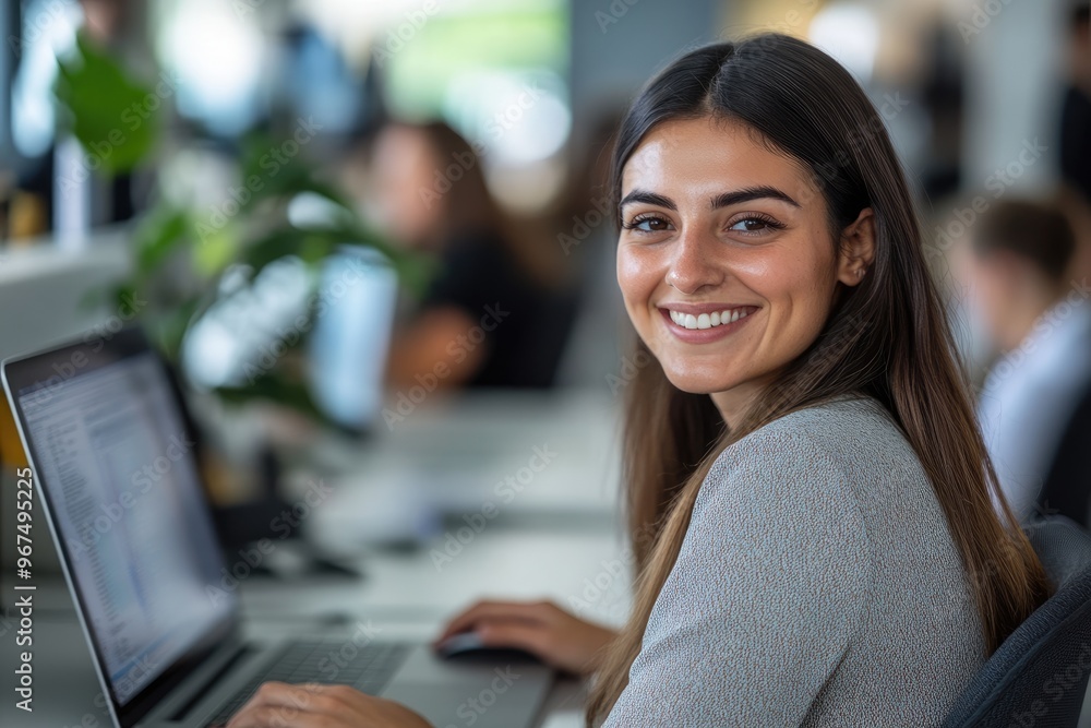 Poster photo of a smiling businesswoman using a laptop while sitting at a desk in an office, working on a c