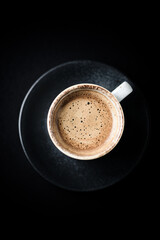 Cup of coffee on dark paper background. Close up. Copy space.