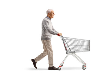 Full length profile shot of a mature man walking and pushing an empty shopping cart