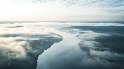 Fototapeta premium A birdâ€™s-eye view of a river winding through a landscape blanketed in morning