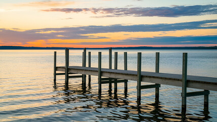 Sunset Serenity Capturing the Tranquil Beauty of a Wooden Dock on a Lake with a Warm Sunset Glow