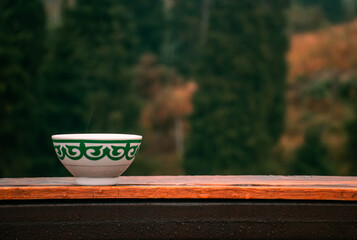 Kazakh bowl piala with national ornament on the wooden table. Autumn mountains on the background. Pefrect photo for Nauryz greetings. Kazakhstan, Almaty, Medeo