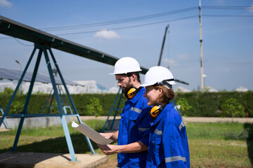 Blue collar workers are working at solar power plant.