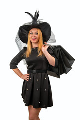 Smiling woman wearing a witch costume for Halloween is holding shopping bags on white background