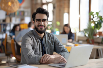 Obraz premium Photo of happy cheerful coder looking at camera, web designing indoors at modern bright workplace, workstation or loft