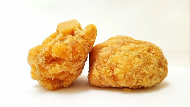 Pieces of Jaggery or Gur isolated rotating on white background, micro shot. Organic brown cane sugar piece isolated
