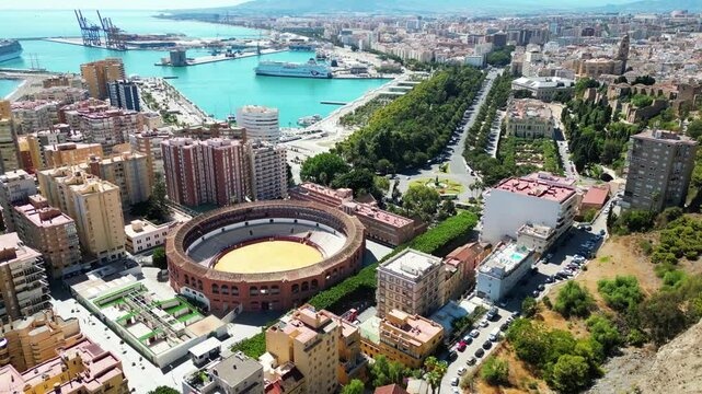 Drone flight over the city center of Malaga (Spain), bullfighting arena, port, sea, townhall and residential sector. Sunny weather, day view.