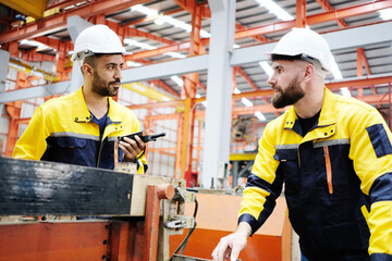 Male engineer works and inspects machinery at a metal sheet factory.