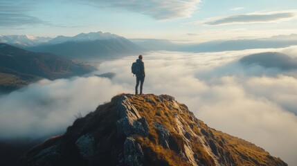 A lone hiker standing on a mountain peak, looking out over a sea of mist that fills the