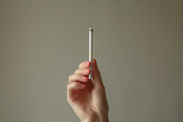Woman hand holding a cigarette on a neutral background