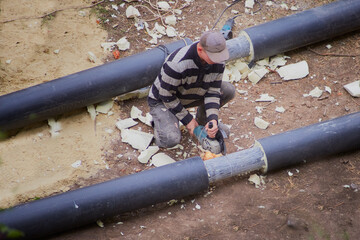 Worker cutting pipe with a hand-held cerular saw
