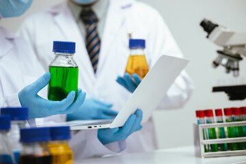 A professional scientist wearing a lab coat and mask conducts research in a laboratory, analyzing liquid samples with a microscope, focused on medical and biotechnological discovery.