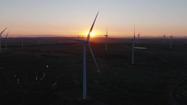 Aerial view of a beautiful wind farm at sunset with wind turbines amidst a scenic landscape, East Kilbride, United Kingdom.
