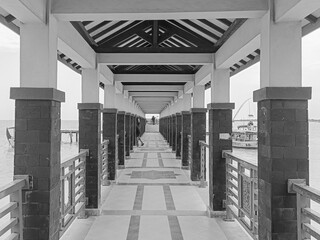 symmetrical covered walkway over water in black and white