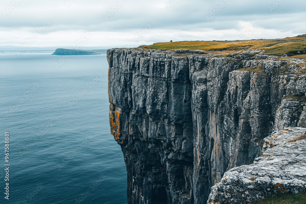 Poster stunning view of a rocky cliff towering over the calm ocean with overcast skies creating a serene sc