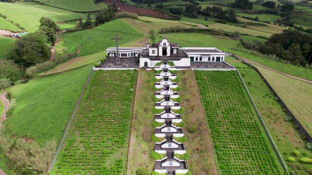 Aerial view of the beautiful Ermida de Nossa chapel surrounded by lush green fields and scenic countryside, Sao Miguel, Azores, Portugal.