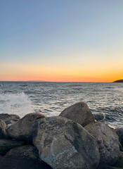 Colorful sunset over the ocean, waves crashing and splashing on rocks