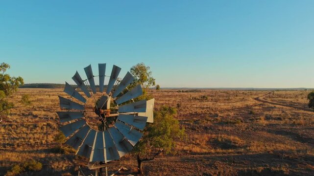 Aerial view of an old windmill in a dry outback landscape at sunset, Emerald, Queensland, Australia.