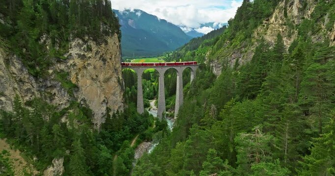 Railway scenic route in Switzerland. Express red swiss train in Swiss Alps. Landwasser Viaduct world heritage sight with luxury Glacier and Bernina express summer scenery