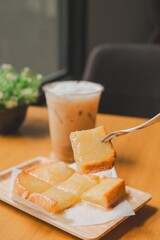 Iced coffee with toast and butter on a tray, served in a cozy cafe setting