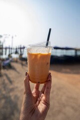 Iced tea in a plastic cup held against a bright blue sky background