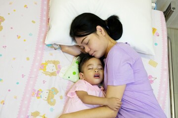 A nurse lying beside a small child in a hospital bed, comforting them.