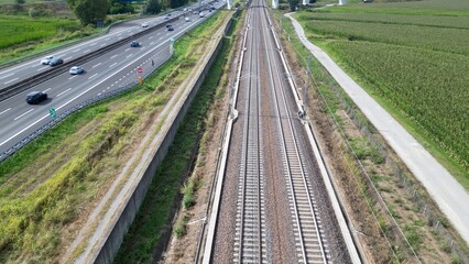 Europe, Italy , Milan 09,14,2024  - Frecciarossa Trenitalia  Hight speed 300km h train railway  view from the drone - the faster way to travel in Italy from Milan to Rome. A1 motorway , cars and train