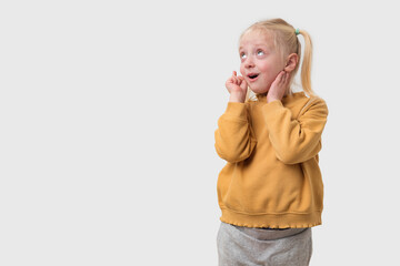 Portrait of a little girl with blond hair in a yellow sweater looking away on a white background