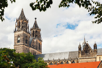 Naklejka premium Magdeburg gothic medieval cathedral Dom church slate tile roof and green trees frame against clear blue sky sunny day. Scenik Saxony-Anhalt sightseeing landmark in Germany