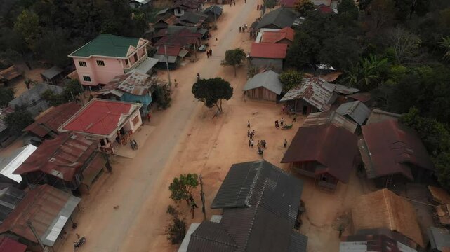 Aerial view of a tranquil village with traditional houses along a dirt road, Sam Neua, Laos.