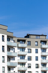 Obraz premium White and beige facade of a newly built apartment block. Clear blue sky above the building. Photo taken on a sunny day