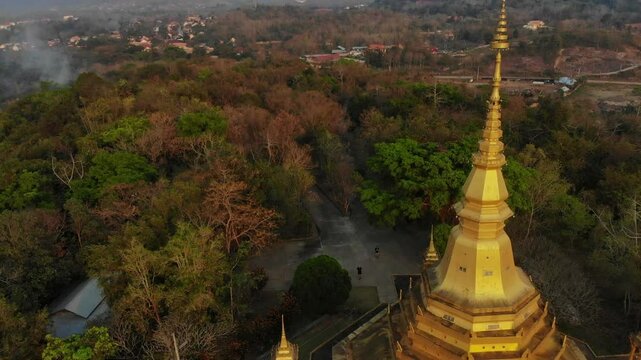 Aerial view of Wat Pa Phon Phao temple at sunset surrounded by lush forest, Luang Prabang, Laos.
