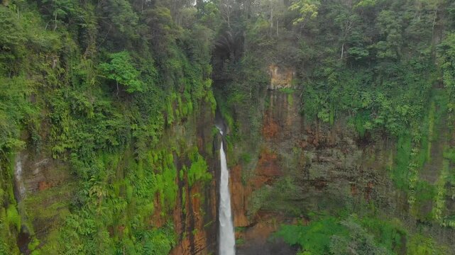 Aerial view of kapas biru waterfall cascading through lush green jungle and forest, Lumajang, Indonesia.