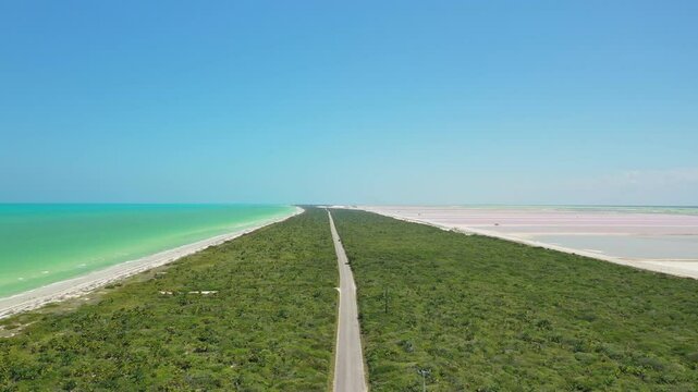 Aerial view of a road separating the pink salt lakes of Las coloradas and the turquoise Caribbean sea on a sunny day