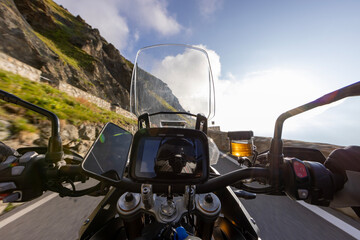 Motorbiker riding in Italian Alps during sunrise, dramatic sky. Travel and freedom, outdoor activities
