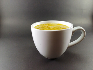 Rich beef steak sauce presented in a white glass cup against a dark grey ash background, highlighting the deep, savory flavors in a simple yet elegant setting