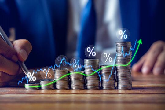 Businessman putting down money, pointing percent with pen and showing candlestick symbol for investing, finance, saving money, interest rate or dividend investment, business growth concept.