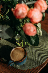 A bouquet of pink and white roses on a wooden table in the living room. A bouquet and a cup of coffee for the woman you love