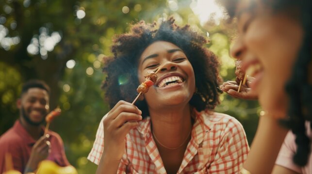 Friends share a joyful moment at a sunny picnic, savoring skewered food and enjoying each other's company in a lush garden.