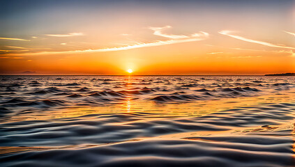 Obraz premium a serene sunset over a calm body of water ,The sun, positioned near the horizon, casts a warm, golden glow across the sky