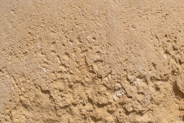 Rough textured beige stone surface with irregular bumps and natural imperfections. Backgrounds